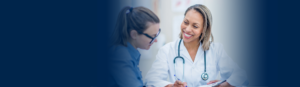 female provider with medical coat and stethoscope smiling towards female patient with glasses