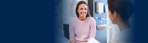 Young adult female sitting on an exam room table smiling at the doctor